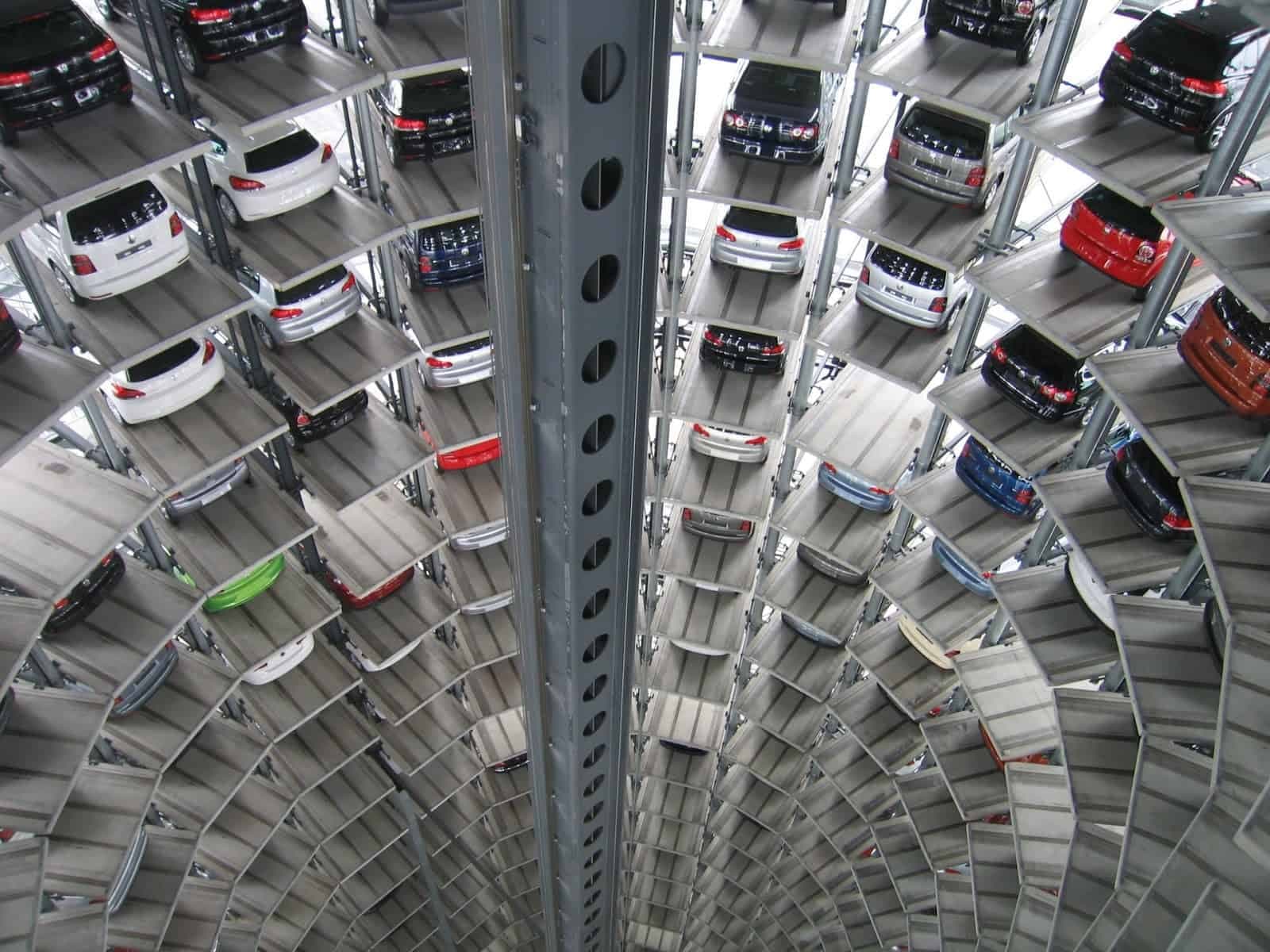 View looking up inside a curved multi-level parking tower with cars stored on each platform