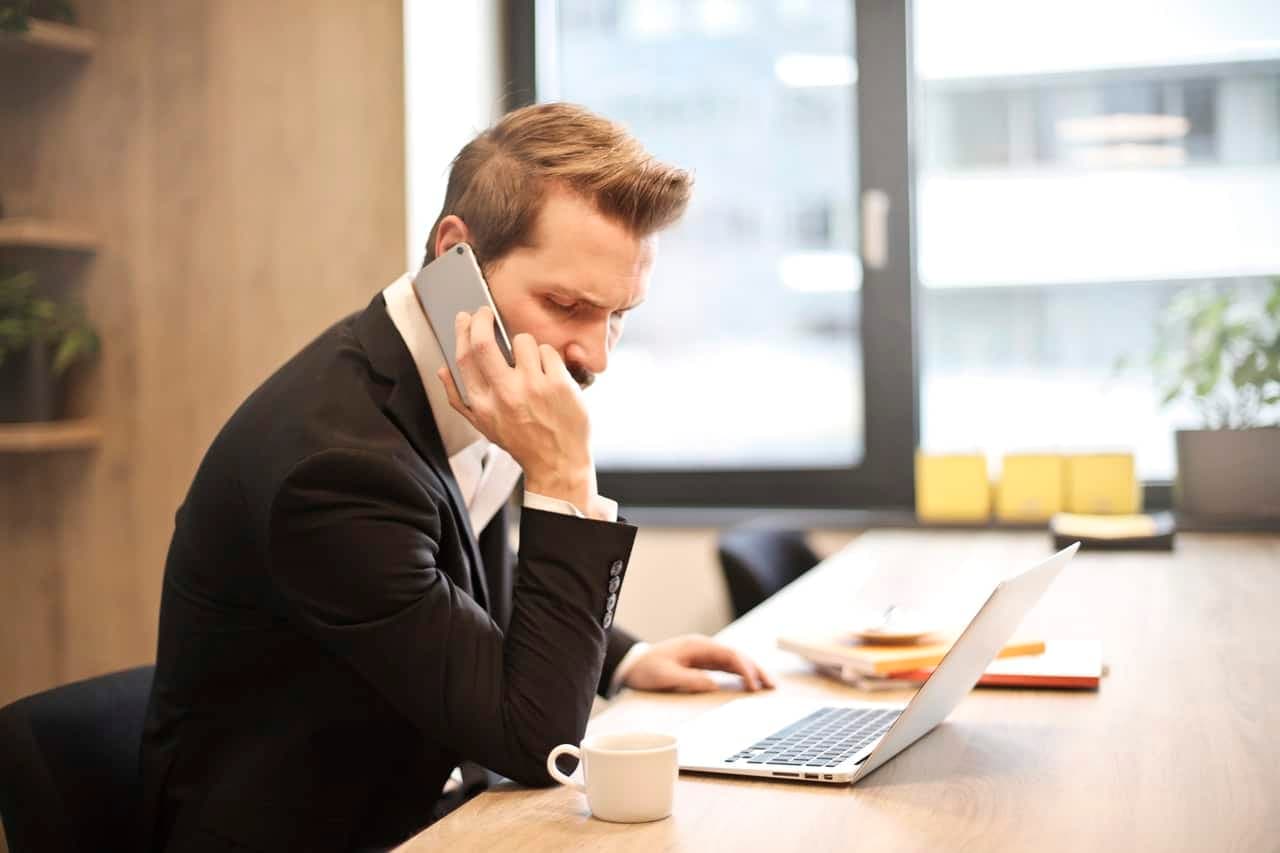 Businessman on phone call at desk working on laptop