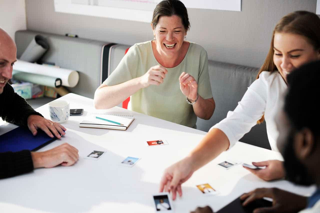 Woman laughing during team meeting with colleagues at table with documents