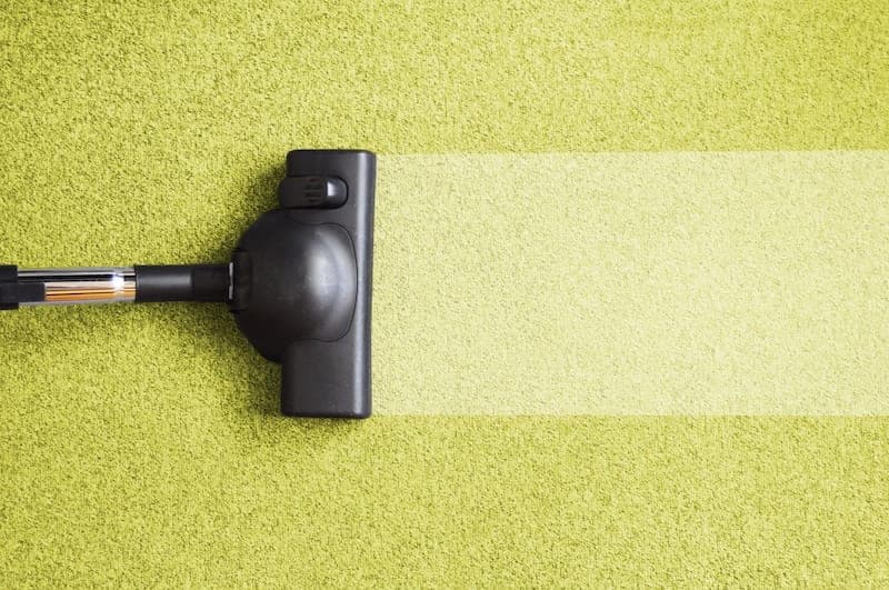 Carpet cleaning machine demonstrating cleaning results on yellow-green carpet