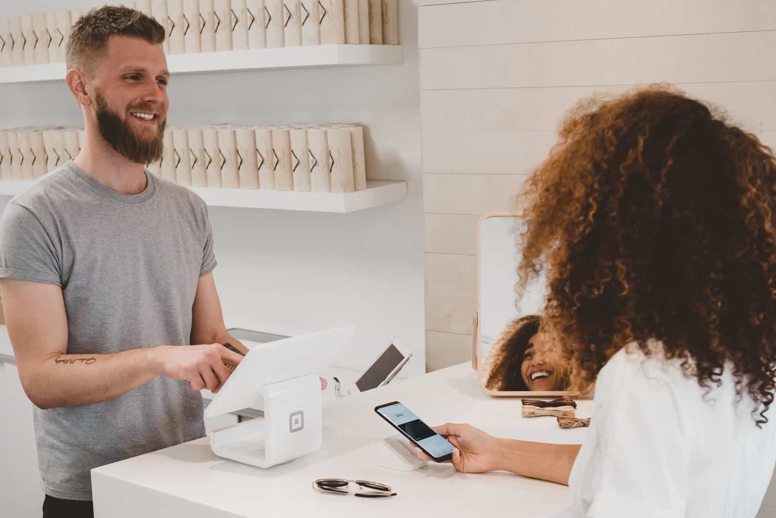 Business staff and customer smiling during payment transaction with mobile device