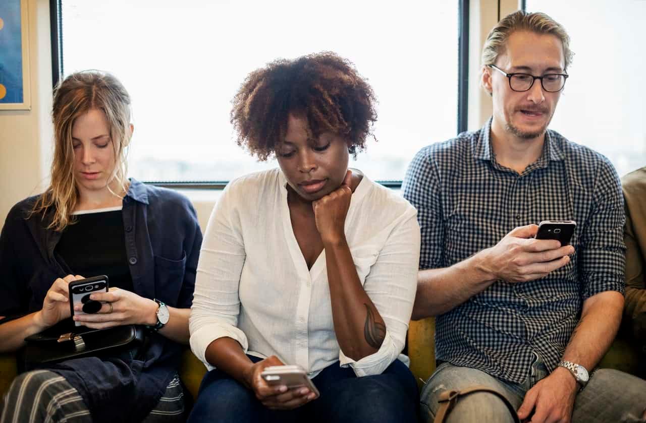Three people on couch focused on smartphones