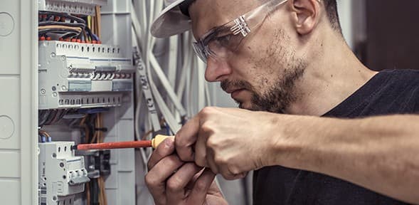 Electrician in safety glasses working on electrical panel