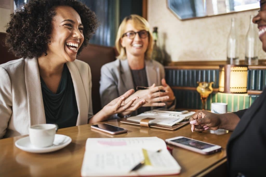 Group of business professionals having conversation at table with coffee