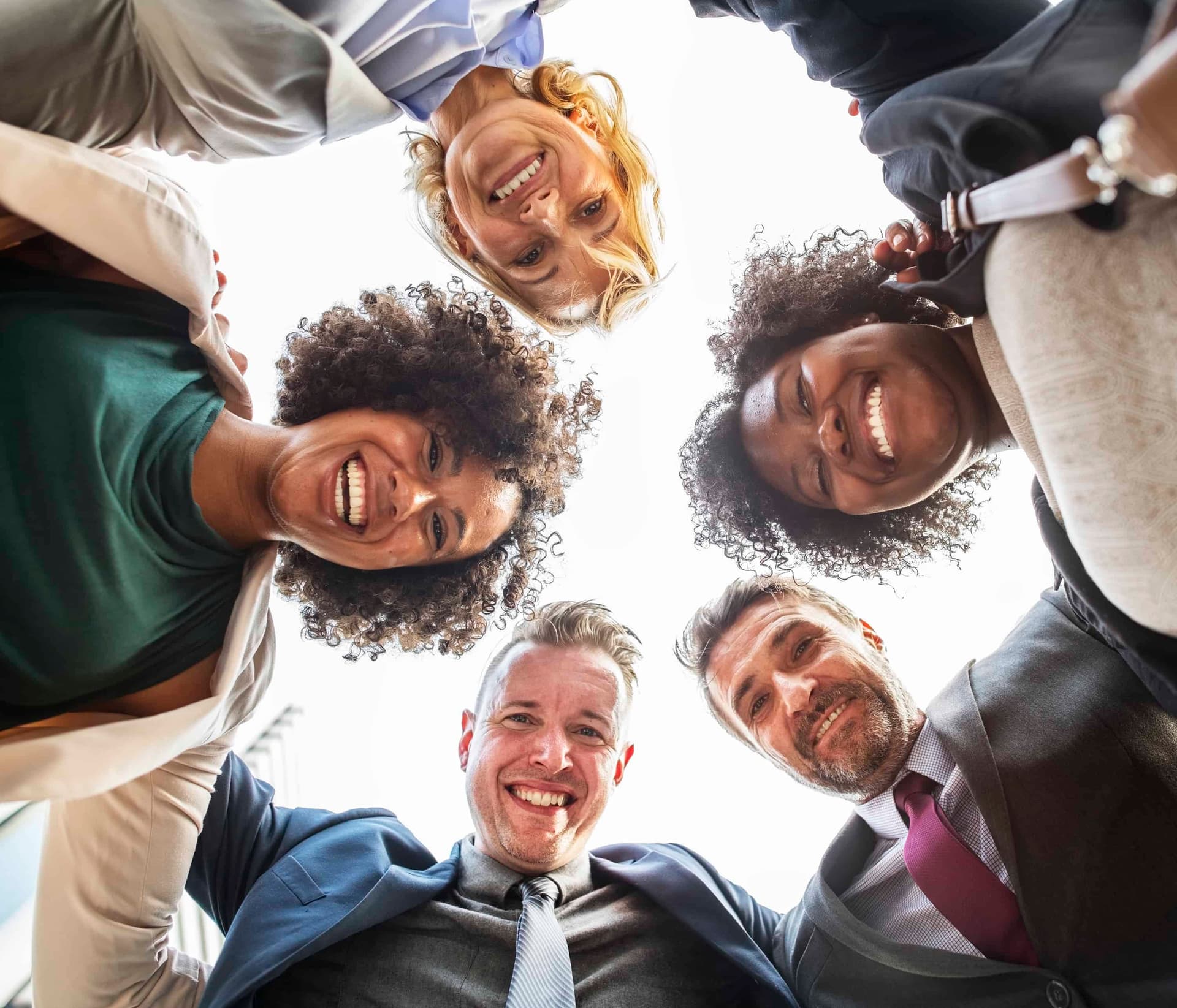 Diverse group of happy people looking down in circle formation