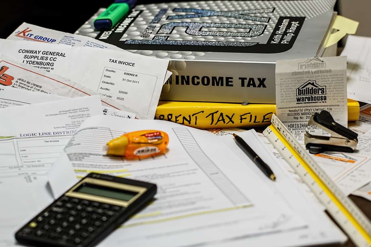 Tax documents, invoices, calculator, and office supplies on work surface
