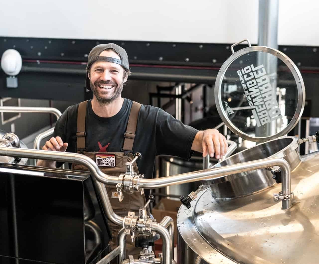 Business owner smiling at brewery equipment with large circular gauge