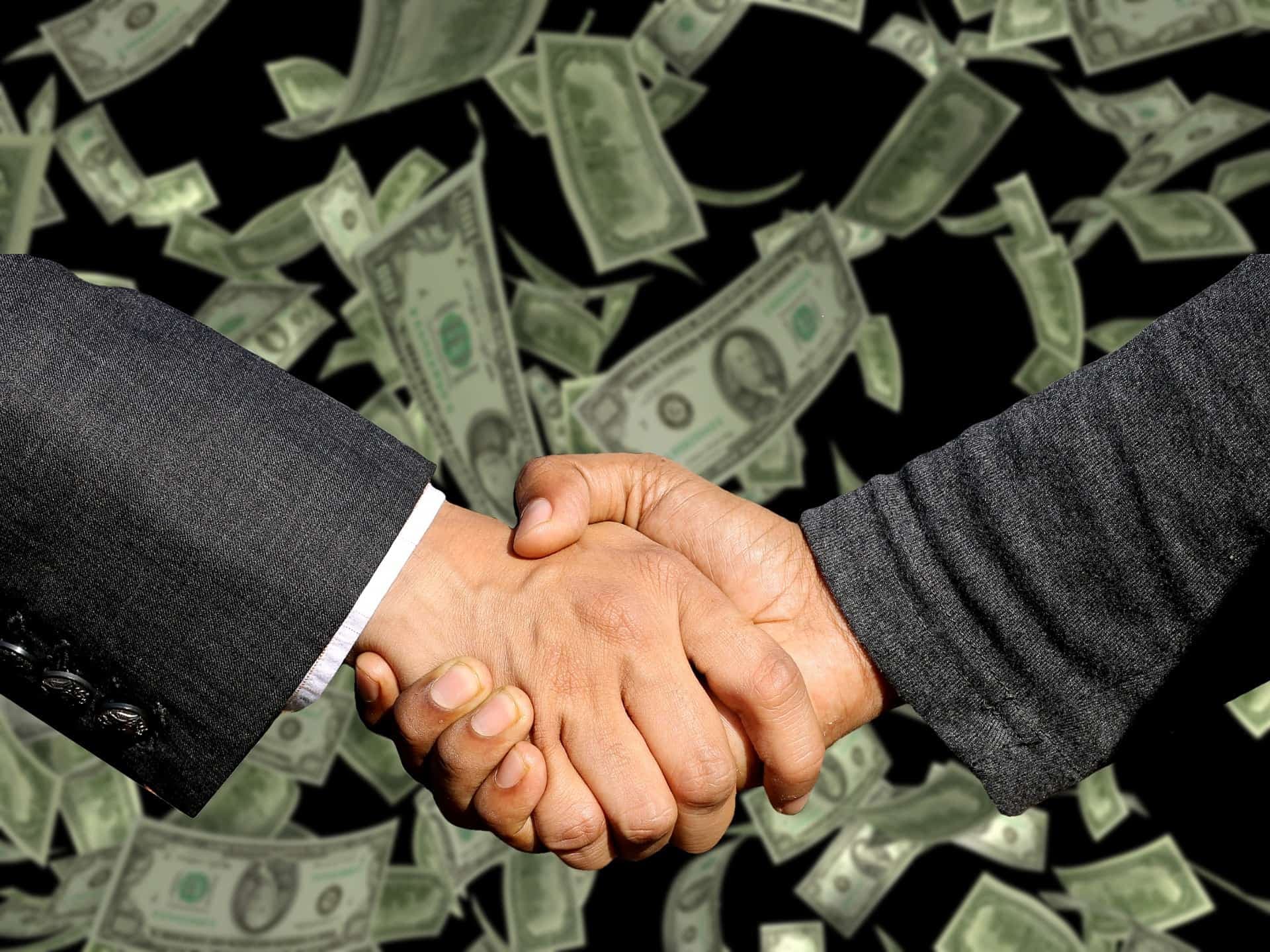 Business handshake with falling dollar bills in background