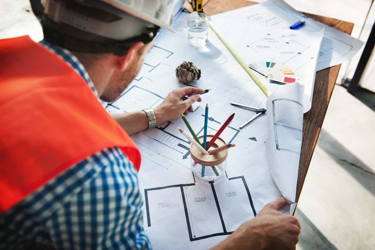 Construction worker in hard hat and safety vest reviewing blueprints and floor plans
