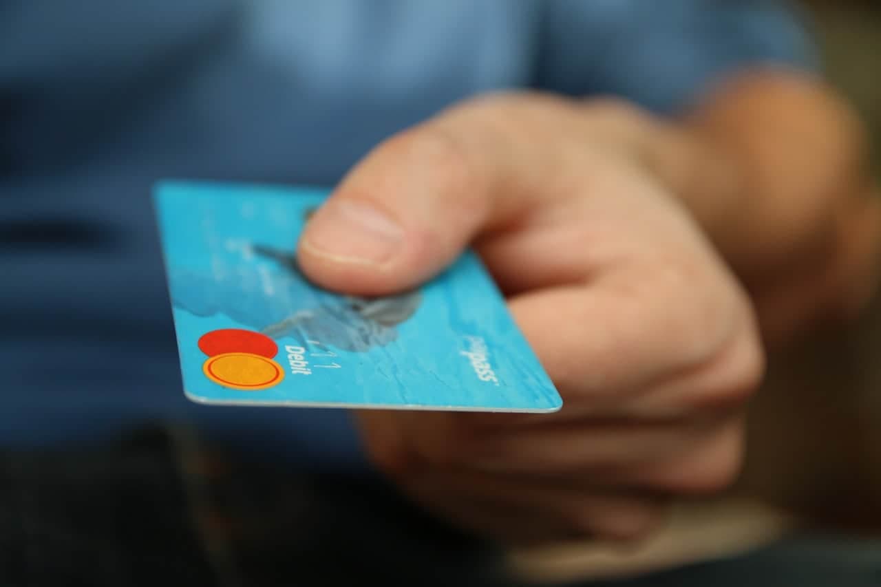 Hand holding blue payment card with colorful processing logo