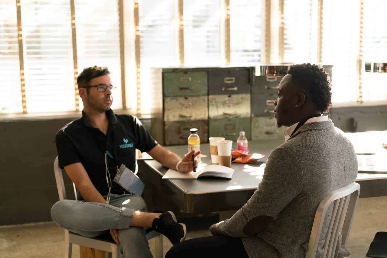 Business professional speaking with colleague while reviewing documents at office table