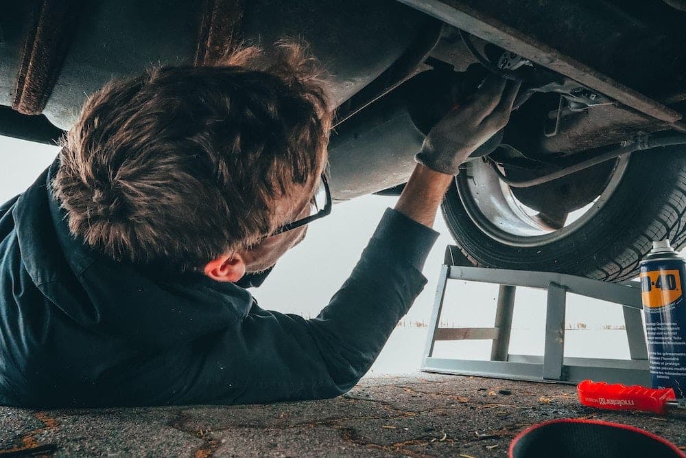 Mechanic lying under vehicle performing maintenance work