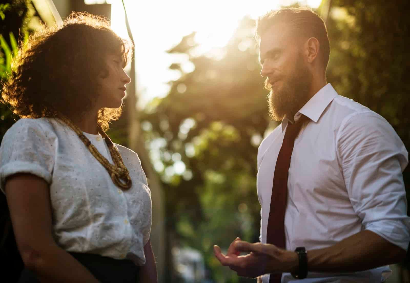 Man and woman in business clothing conversing outdoors in golden sunlight