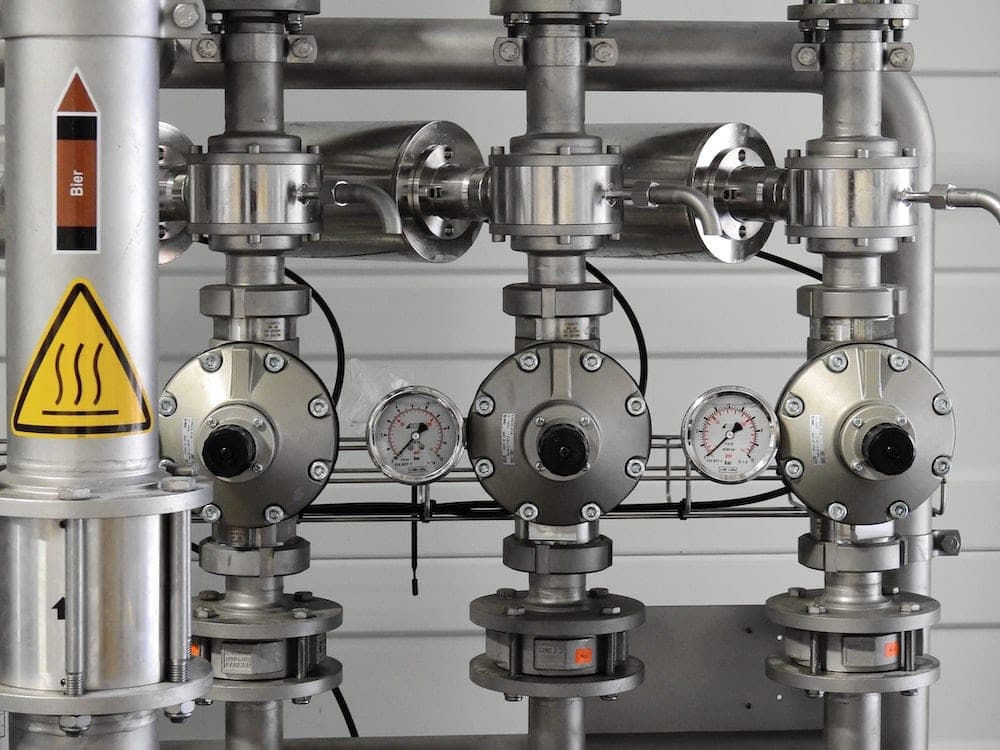 Industrial piping system with pressure gauges and heat warning safety label
