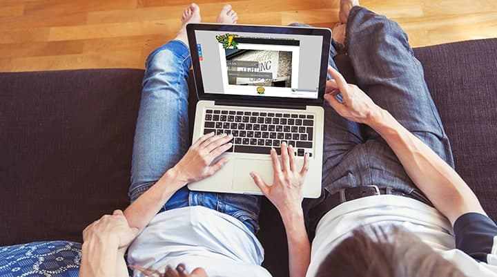 Two people sitting on couch reviewing website on laptop