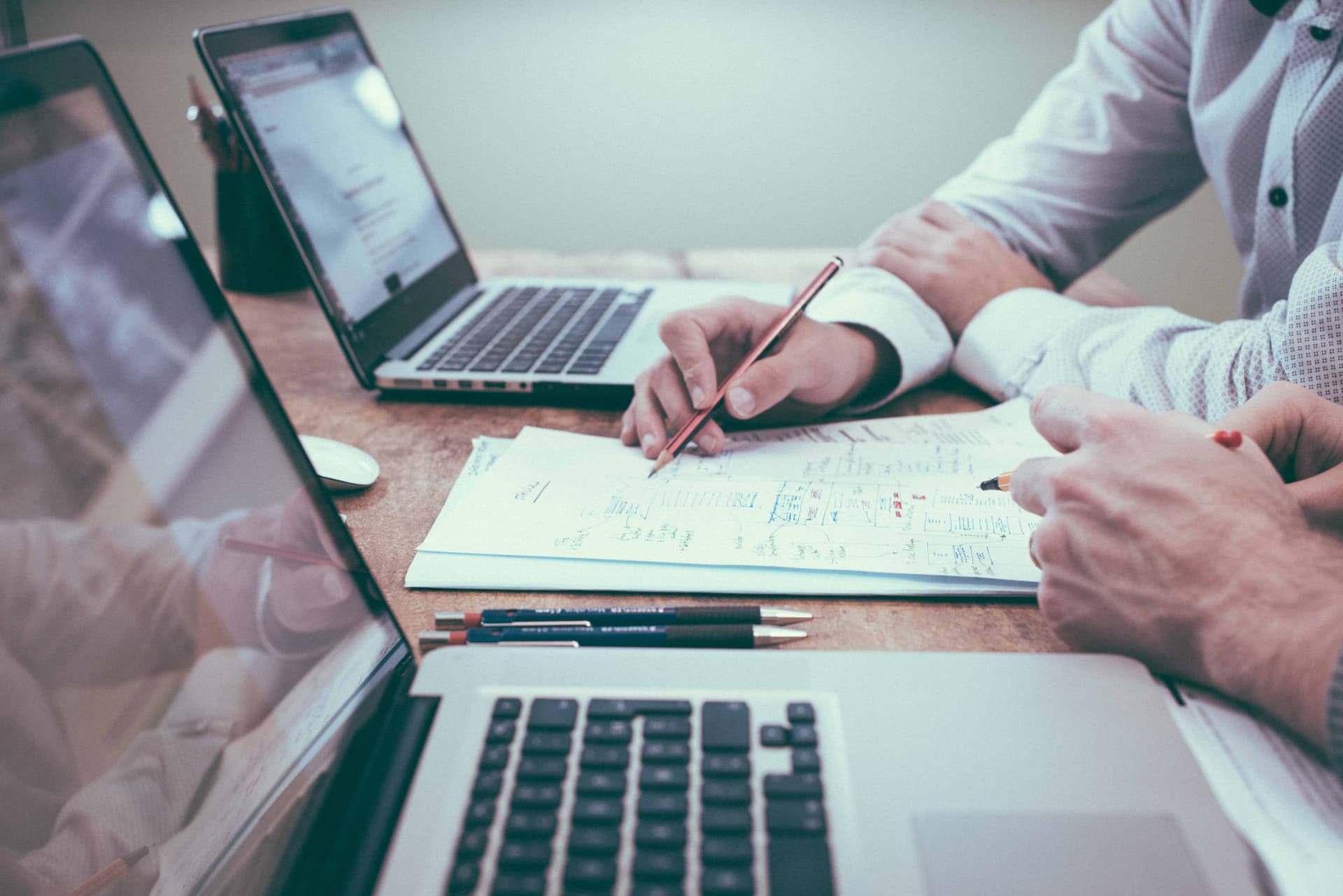 Hands pointing at financial documents with laptop and tablet for business planning