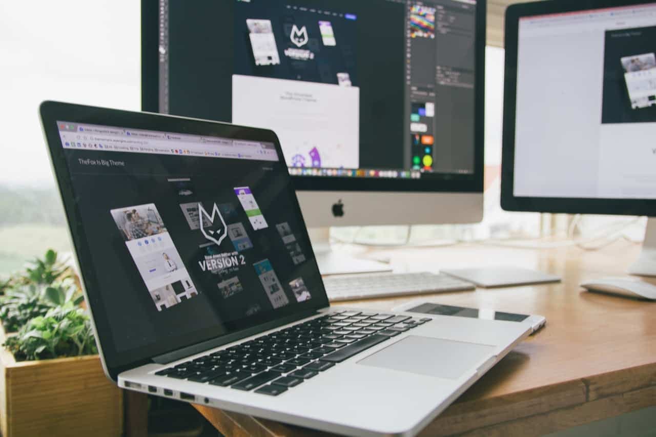 Designer workspace with laptop and multiple monitors on desk