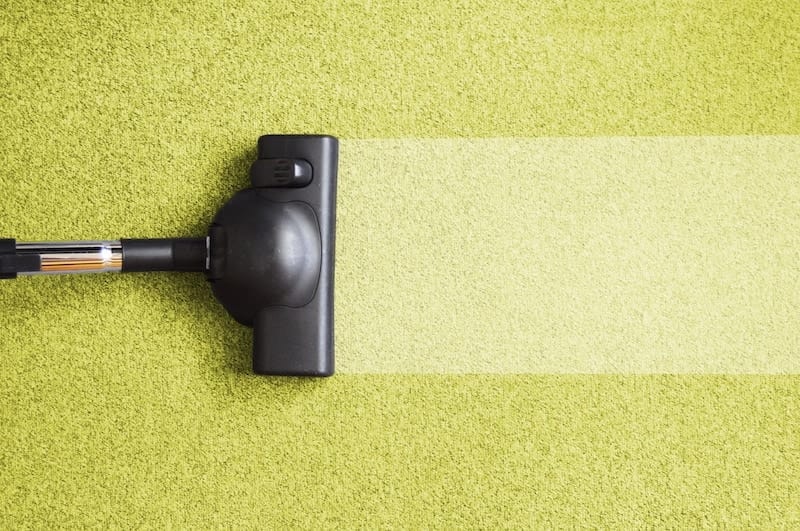 Carpet cleaning machine demonstrating cleaning results on yellow-green carpet