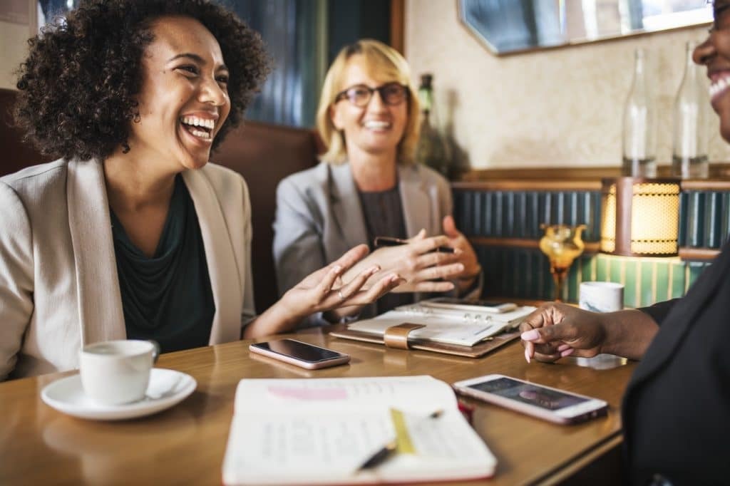 Group of business professionals having conversation at table with coffee