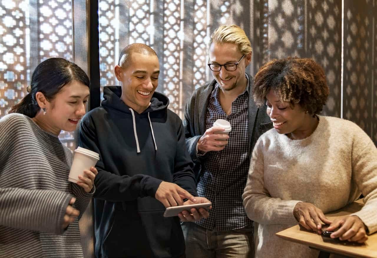 Diverse group smiling while looking at a phone together