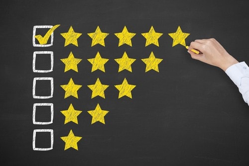 Hand marking checkmark next to five-star rating row on chalkboard