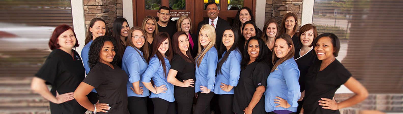 Diverse team of approximately 20 professionals in business attire, mostly wearing blue shirts, posing for group photo