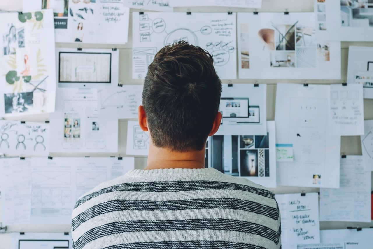 Person viewing wall covered with design mockups, wireframes, sketches, and photos