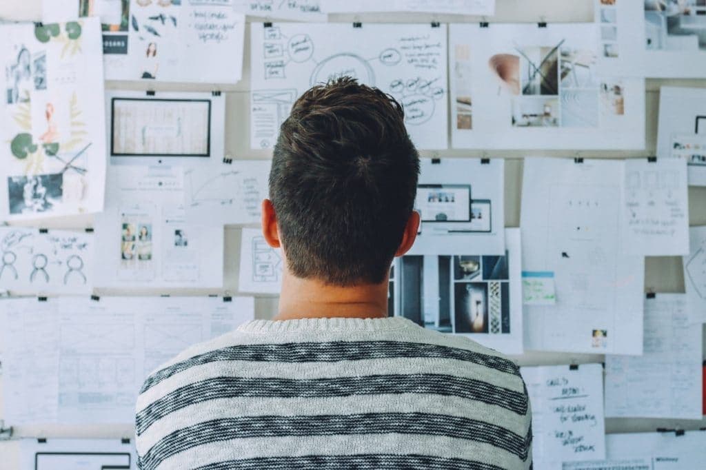 Person reviewing wall covered with sketches and design wireframes