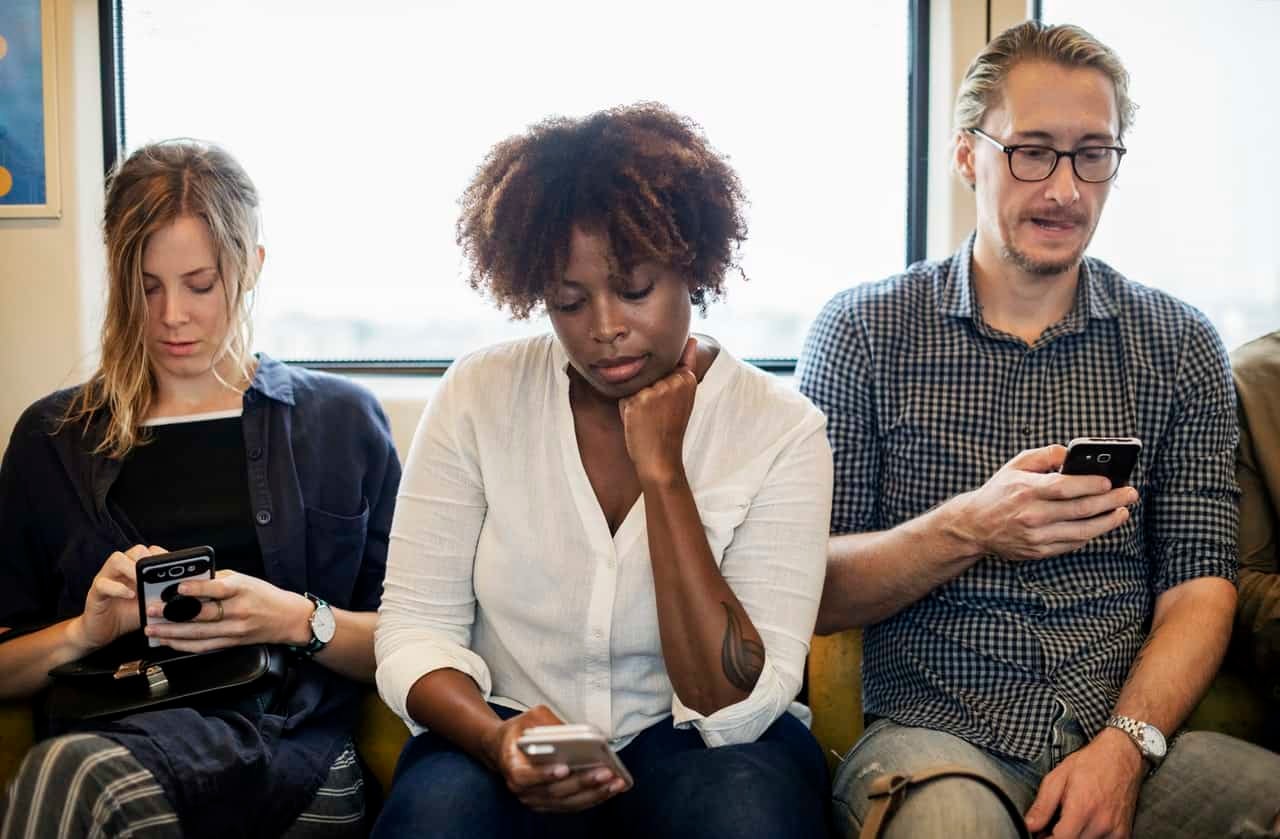 Three people on couch focused on smartphones