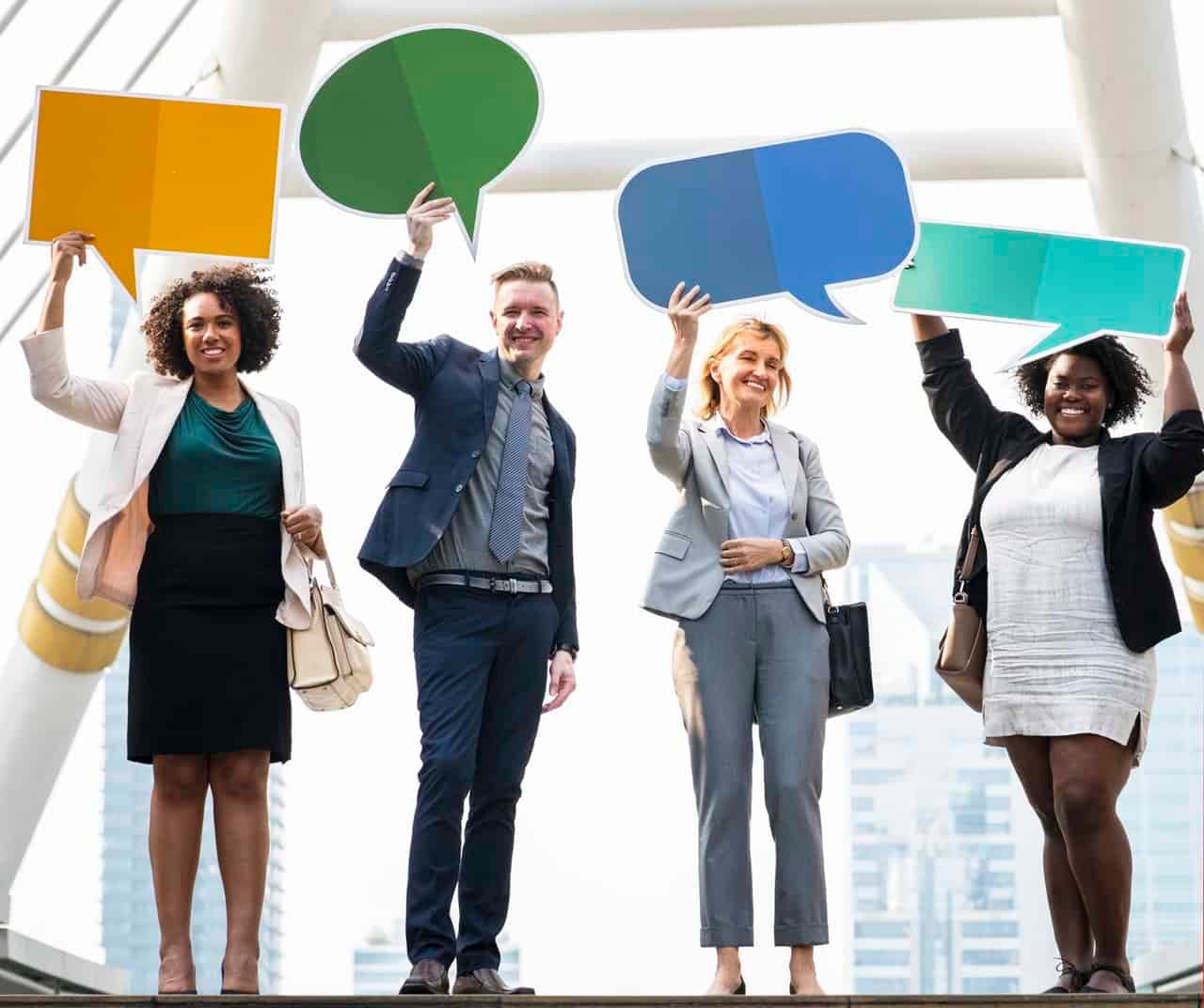 Diverse business team holding colored speech bubbles against office window backdrop