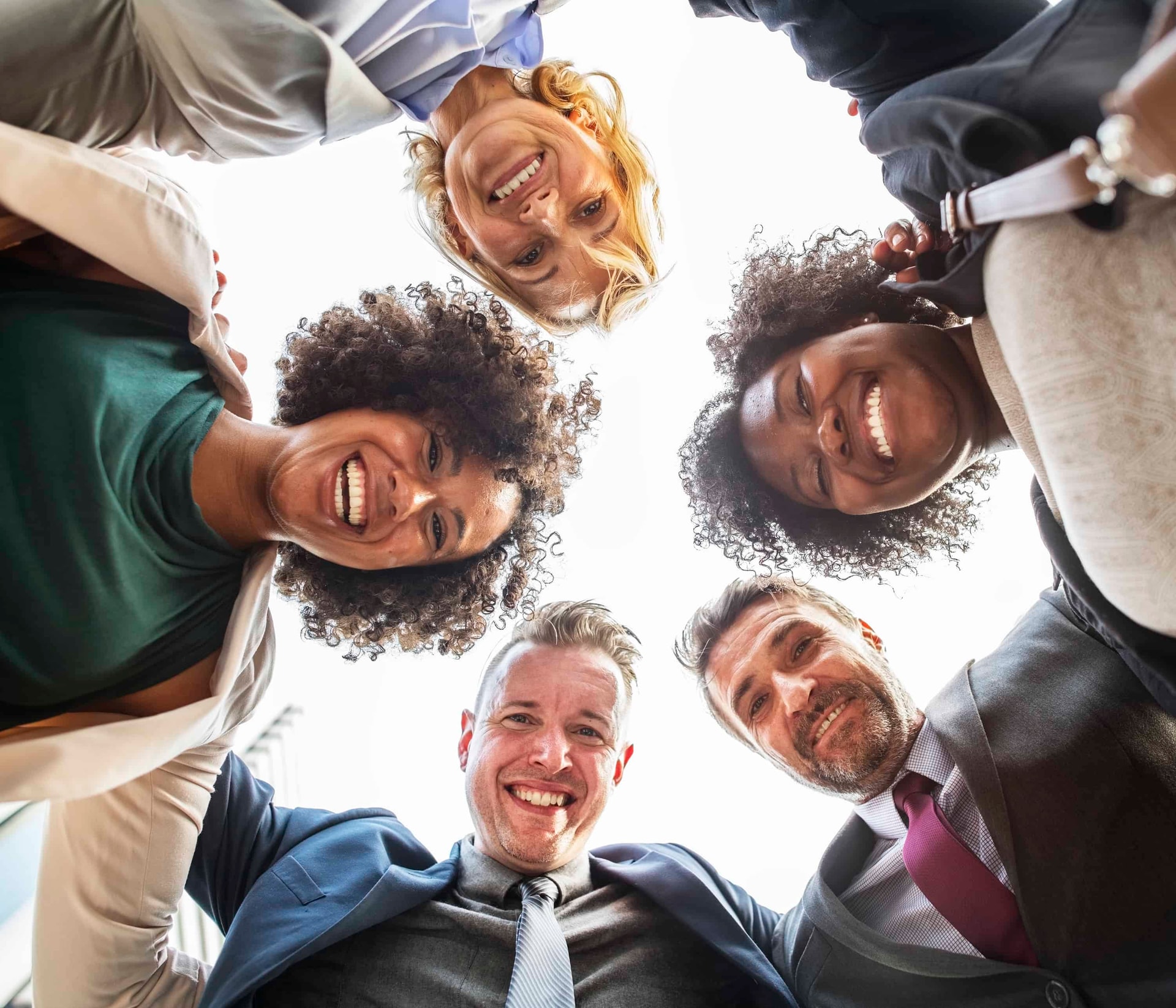 Diverse group of happy people looking down in circle formation