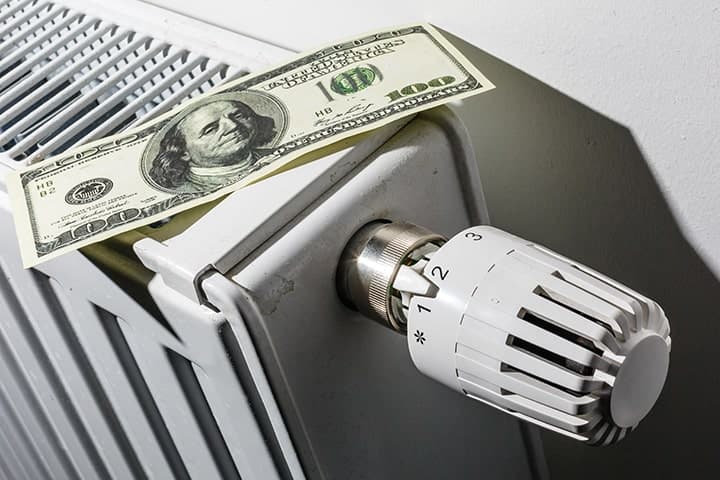 Dollar bill positioned on radiator with thermostatic valve head