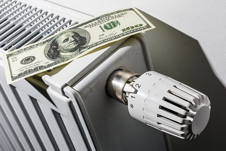 Dollar bill positioned on radiator with thermostatic valve head