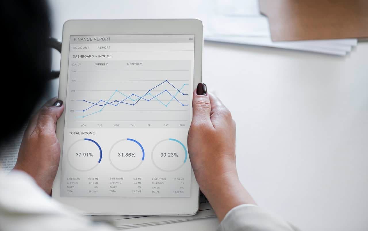 Hands holding tablet displaying finance report with line graphs and income percentage metrics