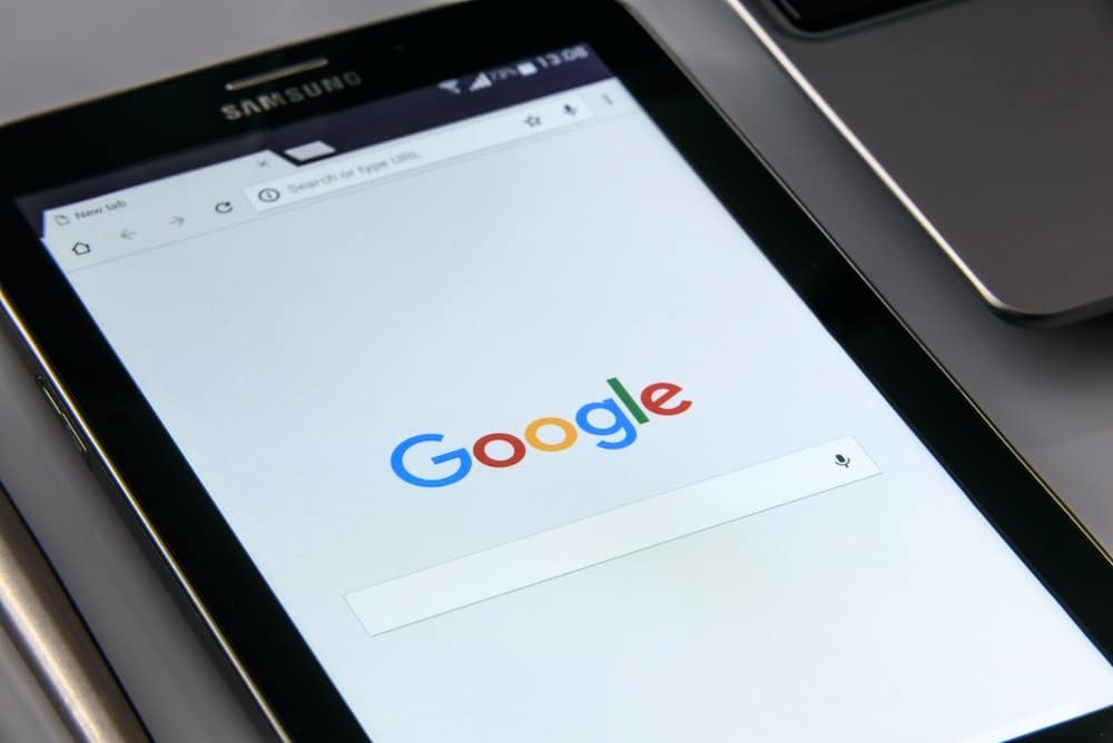 Samsung tablet displaying the Google homepage on a desk next to another device