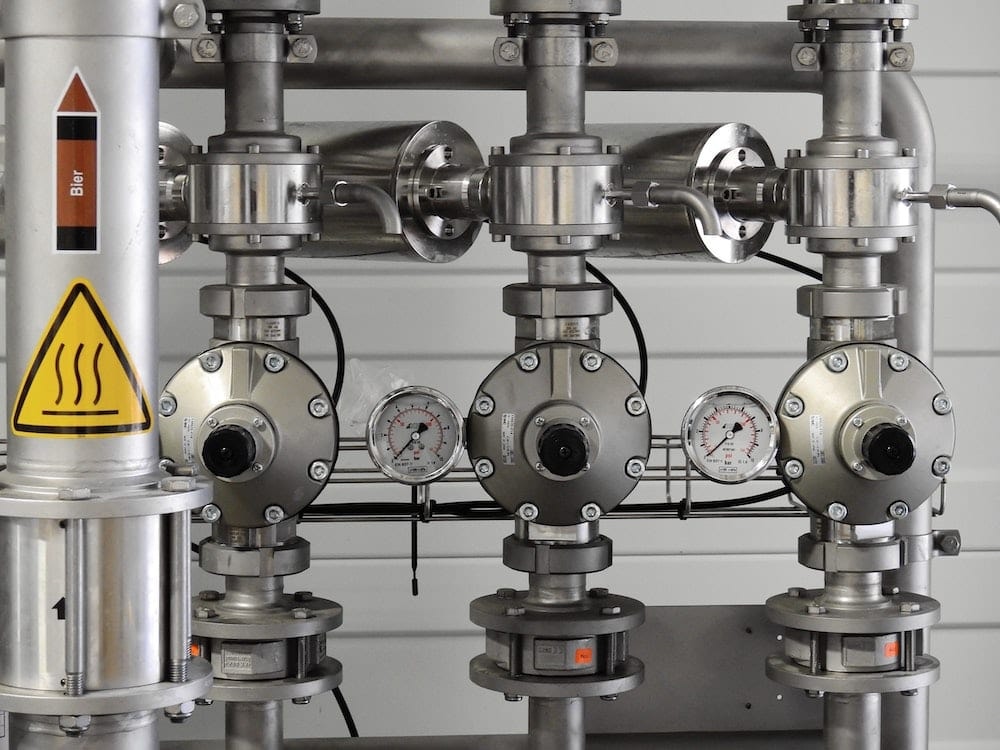 Industrial piping system with pressure gauges and heat warning safety label