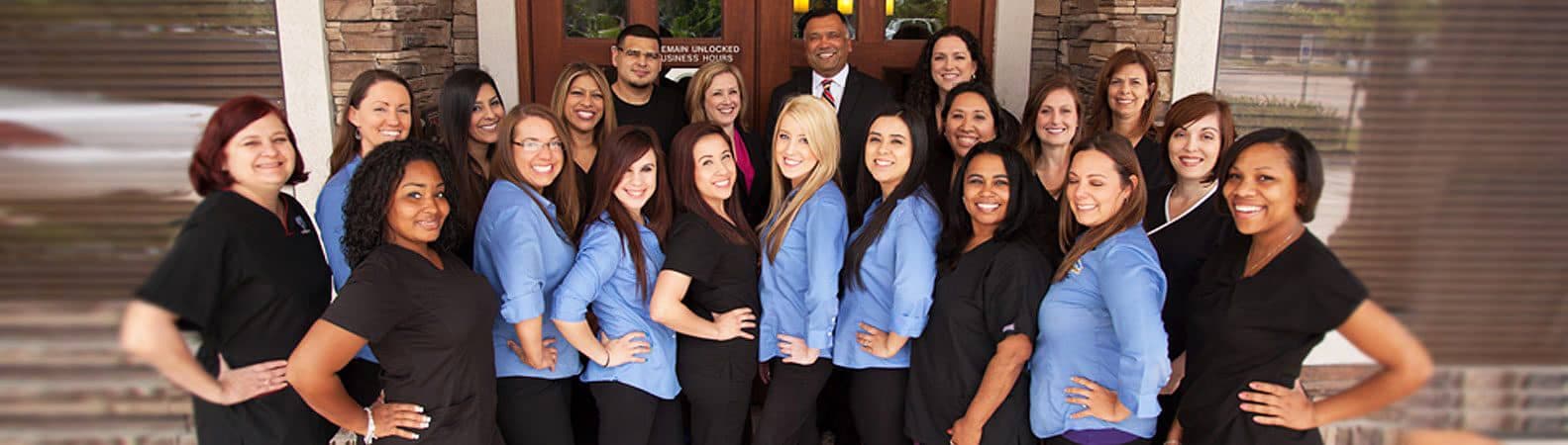 Diverse team of approximately 20 professionals in business attire, mostly wearing blue shirts, posing for group photo