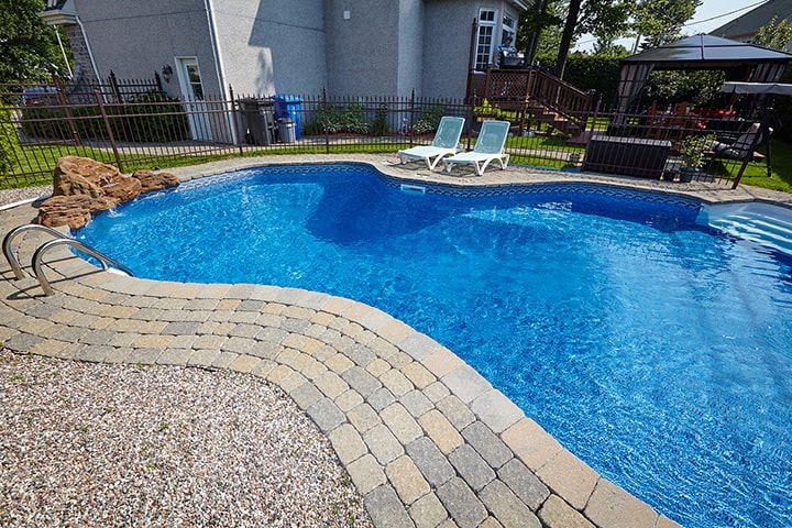 Residential backyard pool with blue water and concrete patio area