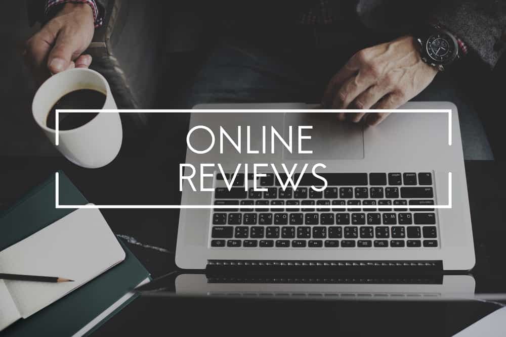 Person at laptop with coffee cup and online reviews text overlay