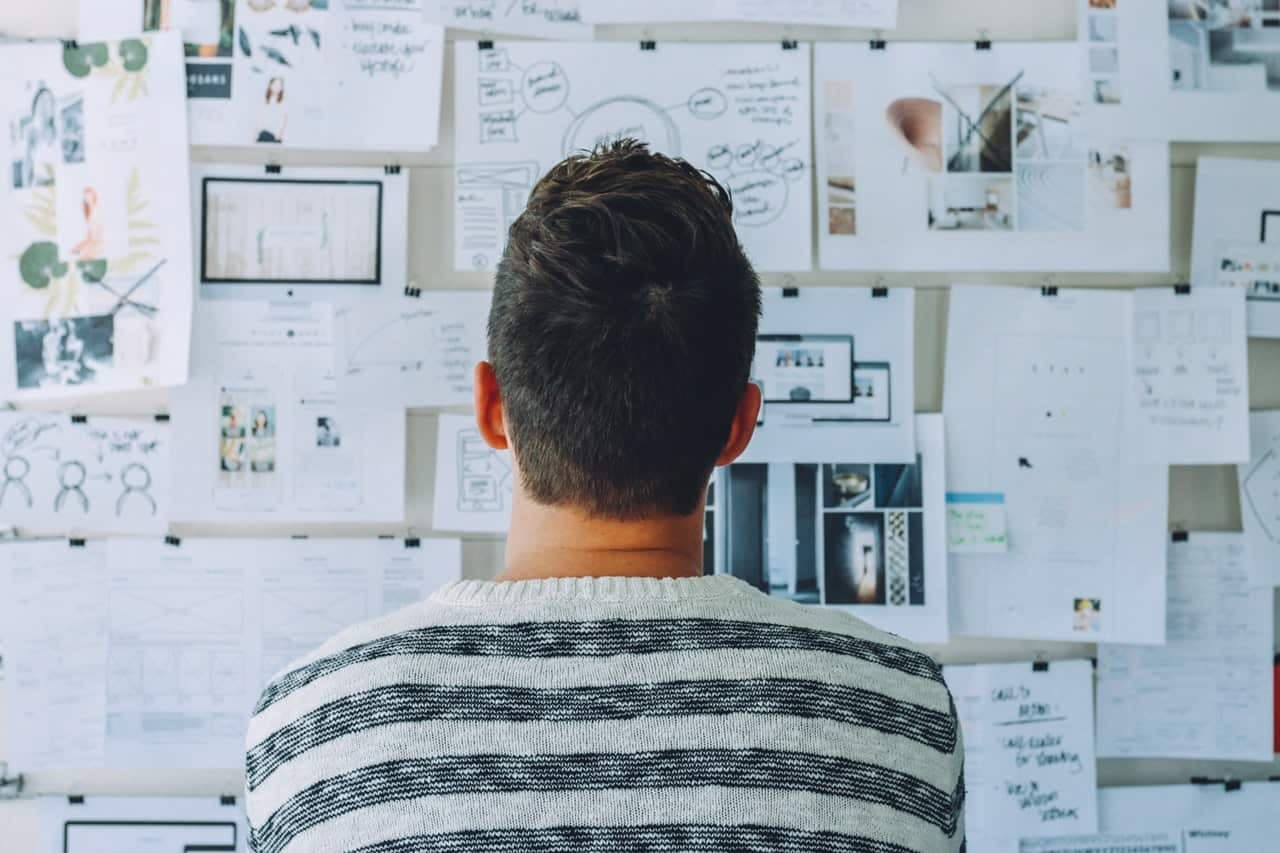 Person viewing wall covered with design mockups, wireframes, sketches, and photos